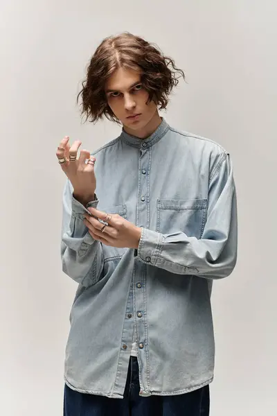 A handsome young man adjusts his jewelry while posing in a minimalist environment. — Stock Photo