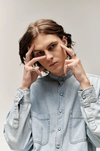 Handsome young man in denim shirt strikes a thoughtful pose against a muted background. — Stock Photo