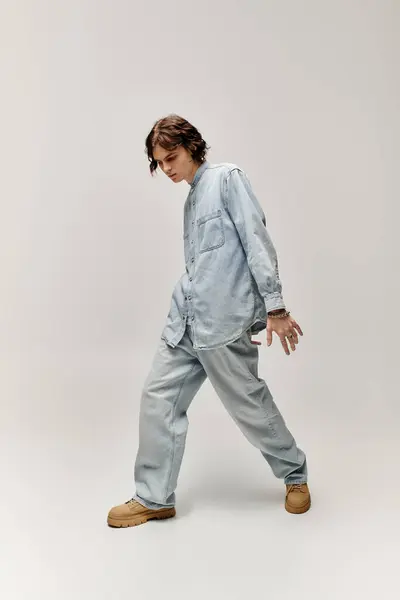 A handsome young man in denim attire strikes a fashionable pose, highlighting his trendy style. — Stock Photo