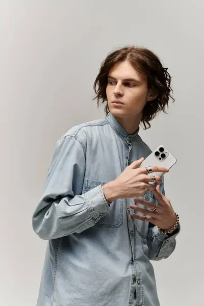 Handsome young man showcases modern fashion while engaging with a smartphone, radiating charm. — Stock Photo