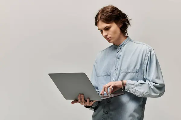 Handsome young man in a denim shirt intensely working on his laptop in an elegant space. — Stock Photo
