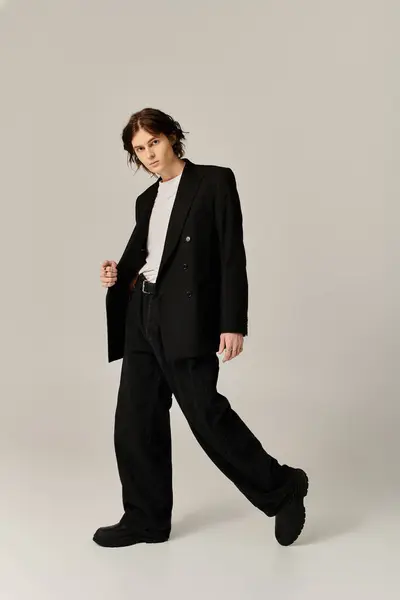 Stylish young man showcases modern fashion with confidence and charisma in a chic studio setting. — Stock Photo
