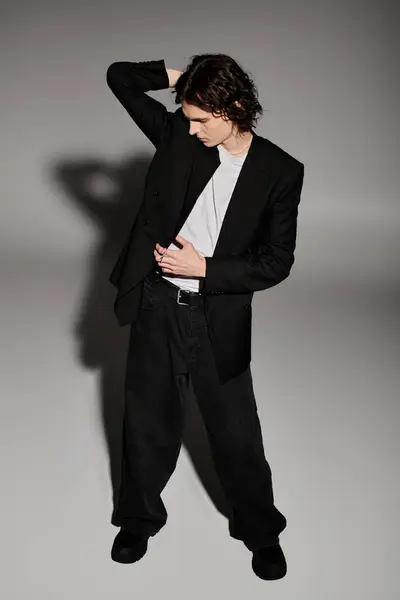 Handsome young man in stylish attire poses thoughtfully against a minimalist backdrop. — Stock Photo