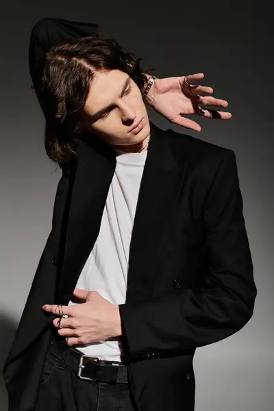 A young man poses confidently in a stylish outfit against a sleek backdrop. — Stock Photo