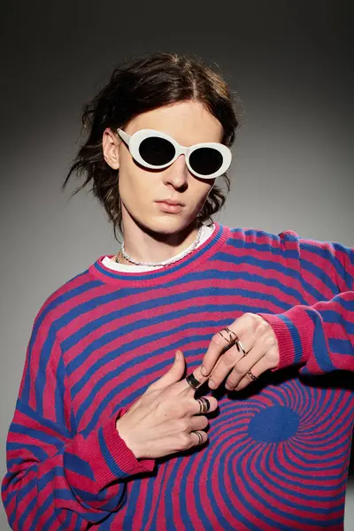 A stylish young man in a colorful striped sweater exudes confidence. — Stock Photo