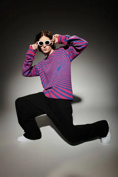 Handsome young man poses confidently, showcasing a unique colorful sweater and trendy sunglasses. — стоковое фото