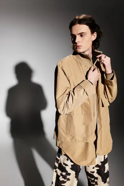 A handsome young man in stylish attire poses confidently, casting a striking shadow. — Stock Photo
