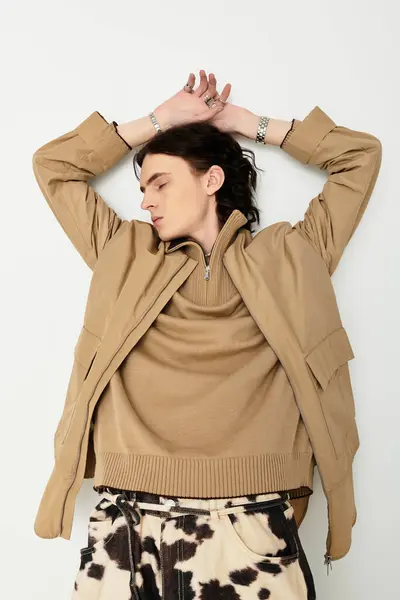 A handsome young man showcases modern style, relaxing with arms raised, exuding confidence. — Stock Photo