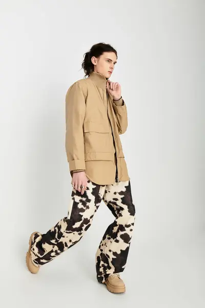 A handsome young man poses confidently in a neutral toned outfit with bold designs, exuding style. — Stock Photo