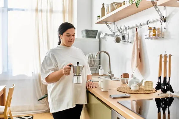 A cheerful young woman prepares coffee in her stylish kitchen filled with light and warmth. — Stock Photo