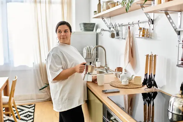 In a bright kitchen, a young plus sized woman prepares her morning coffee, radiating warmth. — Stock Photo