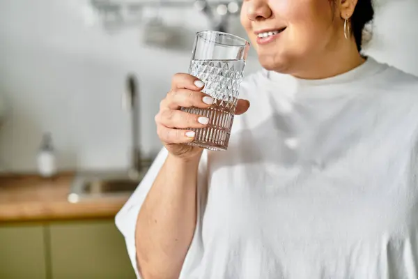 Bright and inviting kitchen scene with a young plus sized woman savoring a cold beverage, smiling. — Stock Photo