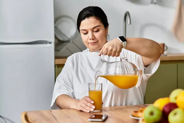 Pouring a glass of fresh juice, a young plus sized woman enjoys a peaceful morning moment. — Stock Photo