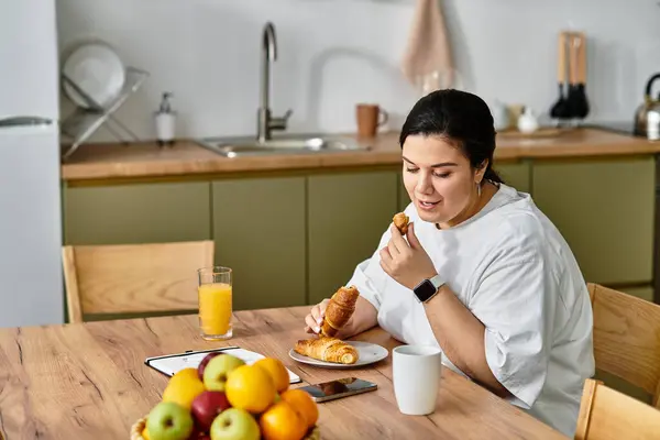 A young plus sized woman savors pastries and fresh fruit, relishing her breakfast moment. — Stock Photo