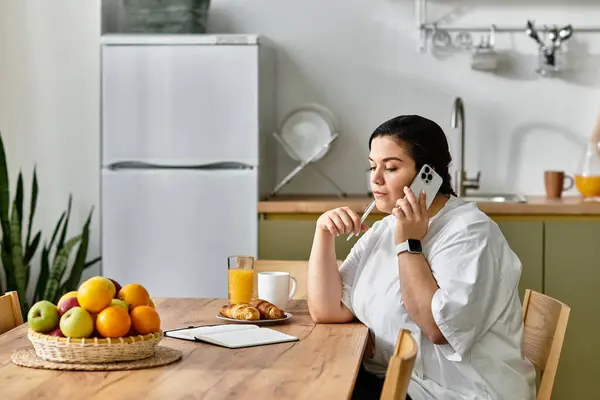 A beautiful young plus sized woman engaged in a phone conversation, enjoying breakfast. — Stock Photo