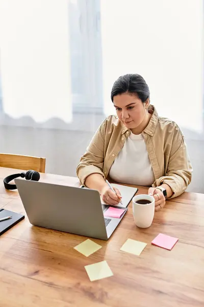 Una hermosa mujer de tamaño grande se centra en su computadora portátil mientras disfruta de su café de la mañana. — Stock Photo