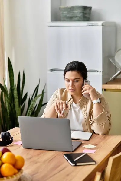 Uma jovem mulher plus size mergulha no trabalho enquanto no telefone em um ambiente acolhedor. — Fotografia de Stock