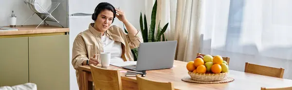 A young plus sized woman sits at a wooden table, working on her laptop with curiosity and focus. — Stock Photo