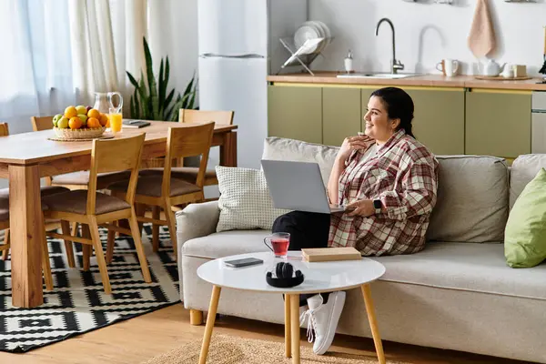 A young plus sized woman enjoys her time in a stylish living space, working on her laptop. — стоковое фото