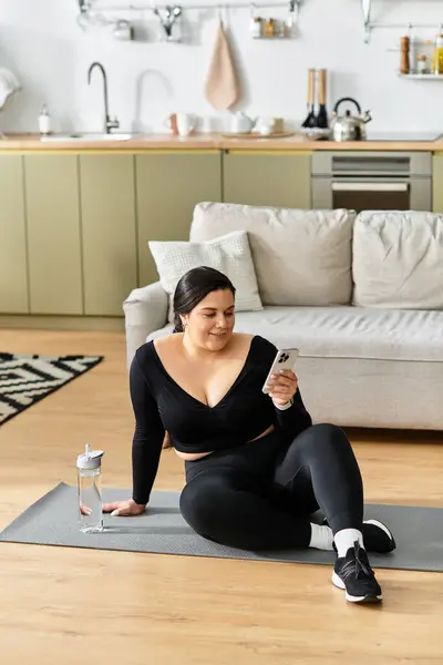 Uma jovem mulher plus size relaxa em seu elegante espaço de vida enquanto verifica seu telefone. — Fotografia de Stock