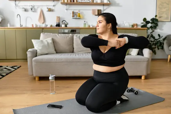 Uma jovem em activewear confortável executa alongamentos em casa, focado em sua rotina de fitness. — Fotografia de Stock
