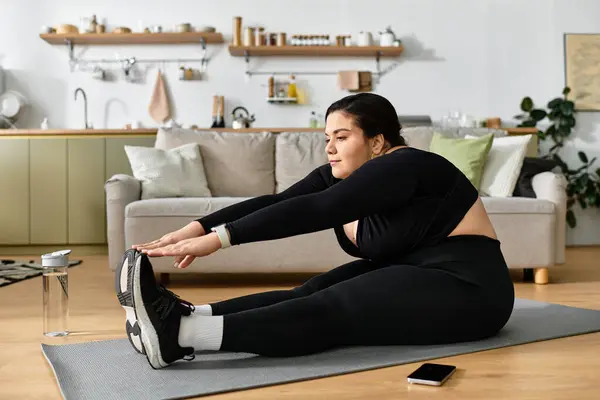 A young plus sized woman enjoys stretching on a mat in her warm and inviting living space. — Stock Photo
