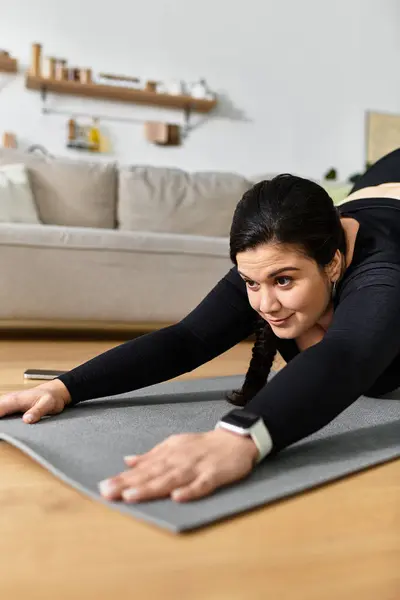 Eine junge Plus-Size-Frau dehnt sich auf einer Yogamatte und fördert Körperpositivität und Selbstpflege. — Stockfoto