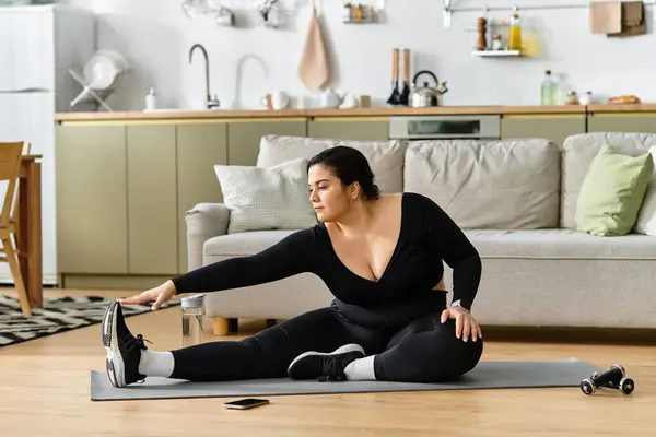 Красивая женщина plus size растягивается на коврике для йоги в своей стильной гостиной. — стоковое фото
