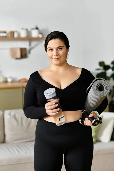 A young plus sized woman stands proudly in her living room, ready for a workout with her gear. — Stock Photo