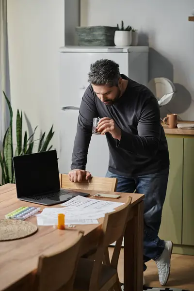 Une personne concentrée examine la paperasserie tout en prenant un verre dans un espace de vie élégant. — Photo de stock