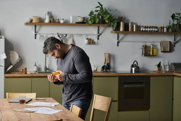 A charming man slices fresh ingredients in his cozy kitchen, radiating warmth and creativity. — Stock Photo