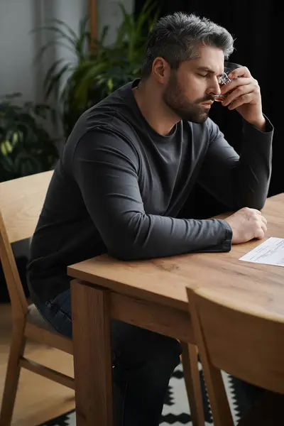 A thoughtful man rests his forehead on his hand, surrounded by greenery, lost in deep reflection. — Stock Photo