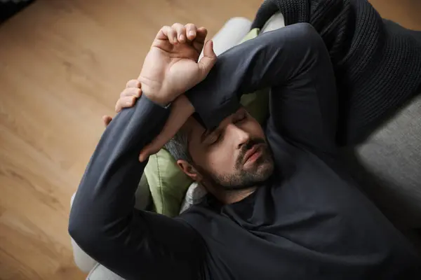 Handsome man peacefully resting on a sofa with his arms crossed, enjoying a calm afternoon. — Stock Photo