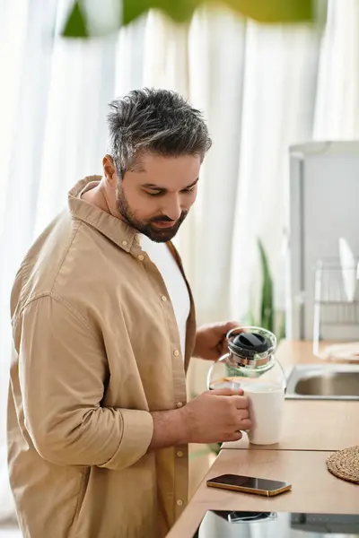 Un hombre encantador prepara su té de la mañana mientras disfruta del ambiente sereno de la cocina. — Stock Photo