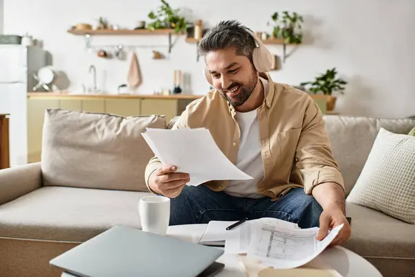 A handsome man reviews important documents while relaxing on a comfortable sofa at home. — Stock Photo
