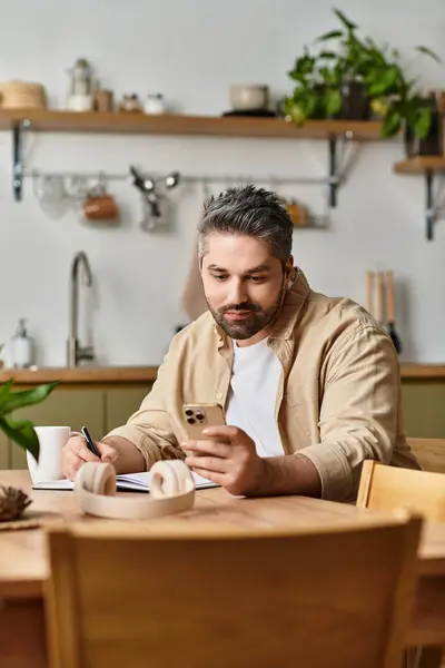 Bell'uomo studia attentamente il suo smartphone, circondato da piante e un arredamento minimalista. — Stock Photo