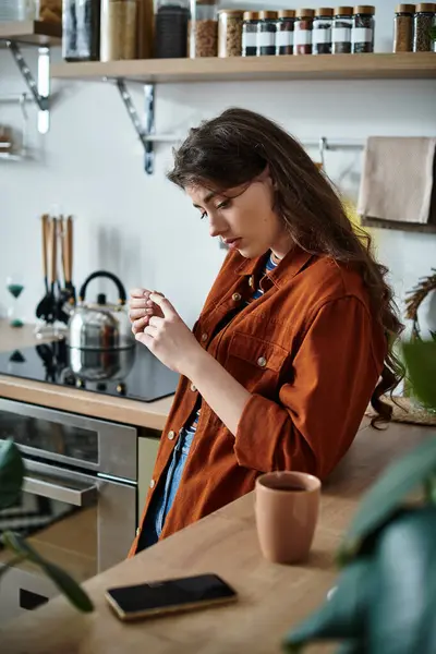 A woman reflects on her feelings while standing in a warm kitchen space. — Stock Photo
