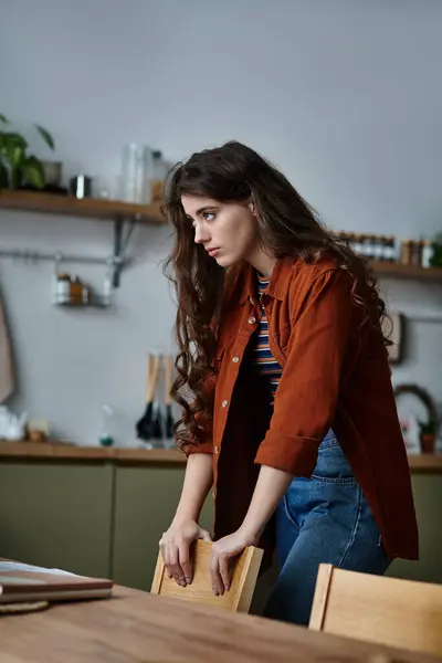A woman stands in a calm kitchen, lost in thought, facing her inner turmoil and sadness. — Stock Photo