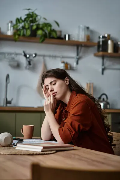 Una donna poggia la testa sulla mano, persa nel pensiero, circondata da una serena atmosfera da cucina. — Foto stock