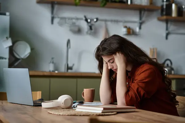 A woman sits at a wooden table in a warm kitchen, overwhelmed by her feelings. — Stock Photo