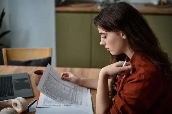 A woman sits at a table, absorbed in her paperwork, reflecting feelings of sadness and anxiety. — Stock Photo