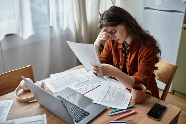 A woman sits at a table surrounded by papers, feeling the weight of her thoughts deeply. — Stock Photo