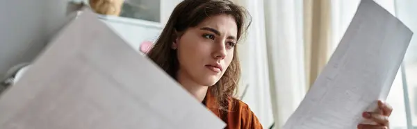 A woman appears lost in thought as she examines papers, reflecting feelings of depression. — Stock Photo