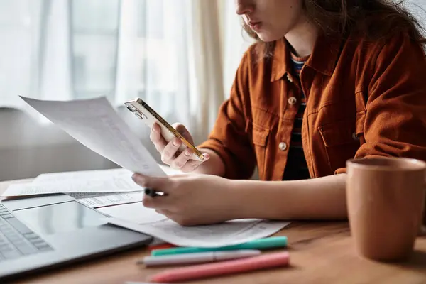 In a warm, sunlit room, a woman struggles with her emotions as she reviews documents on her desk. — Stockfoto