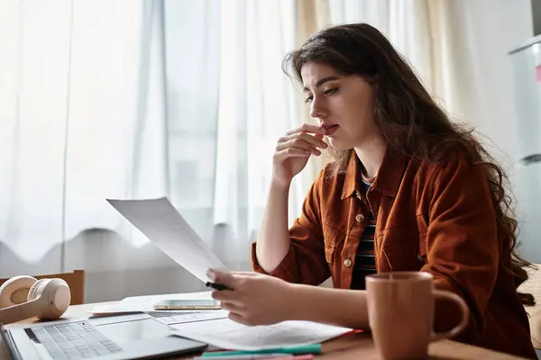 A woman sits at a table, deeply absorbed in reviewing papers that evoke complex emotions. — Stock Photo