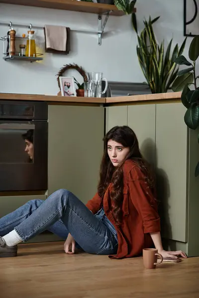 A woman with long hair sits on the kitchen floor, reflecting deep emotions as she contemplates life. — Stock Photo