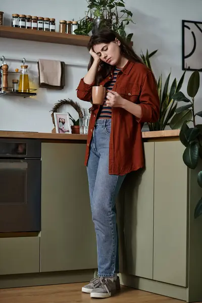 Una donna si trova in una cucina accogliente, in possesso di una tazza, persa nei pensieri delle sue lotte con la depressione. — Foto stock