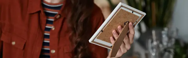 A woman passionately holds a picture frame, lost in her thoughts as emotions swirl within her. — Stock Photo