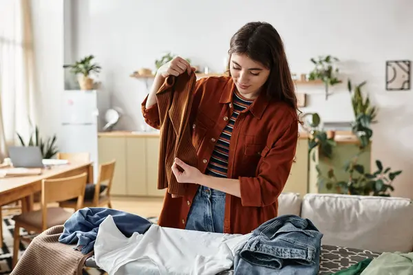 A woman methodically folds laundry in a cozy room, reflecting on her emotions during her day. — Fotografia de Stock