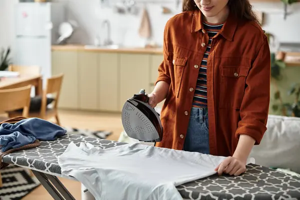 Uma mulher pressiona roupas em sua cozinha acolhedora, exibindo sua luta com sentimentos internos. — Fotografia de Stock